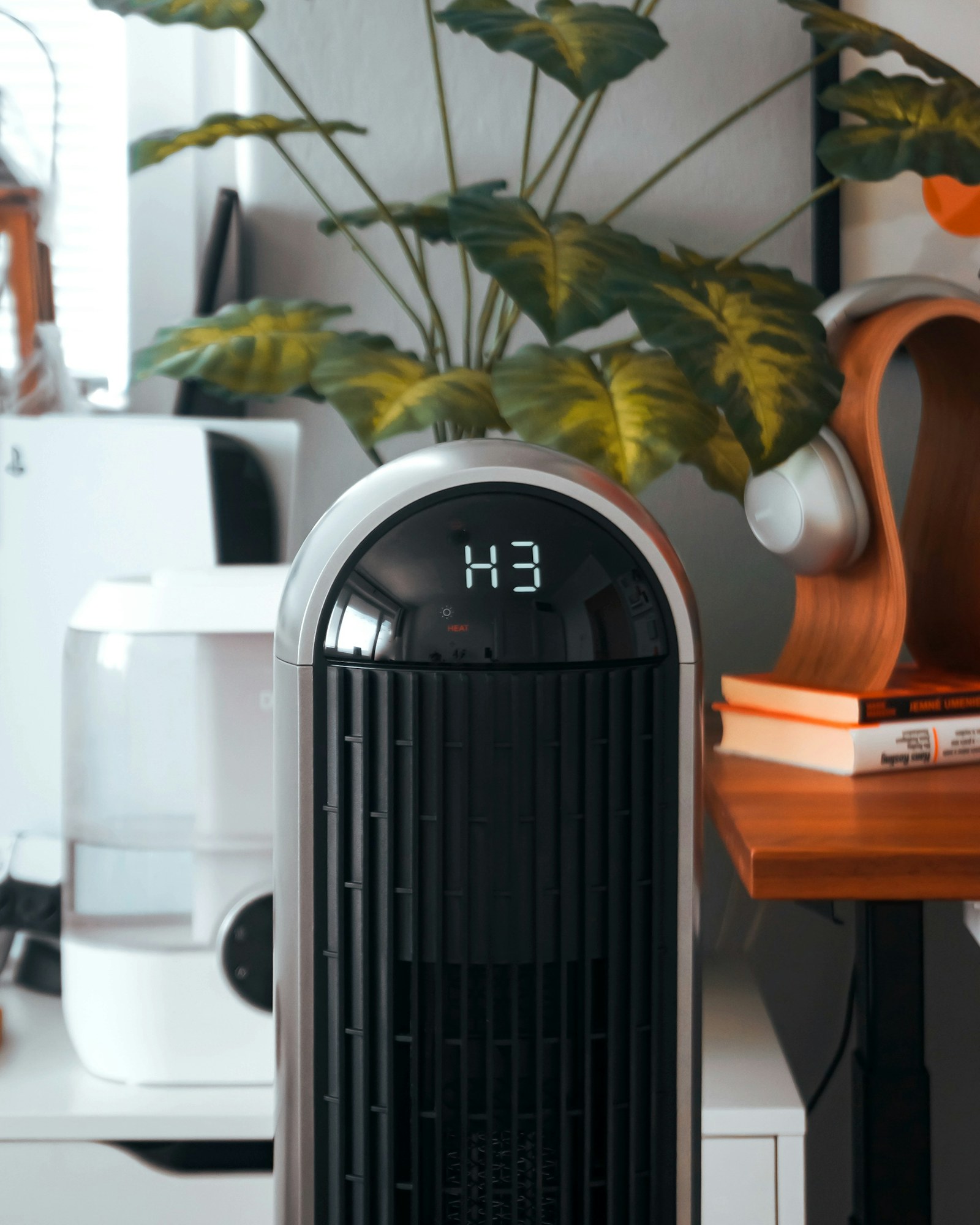 An air purifier in a home workspace beside plants